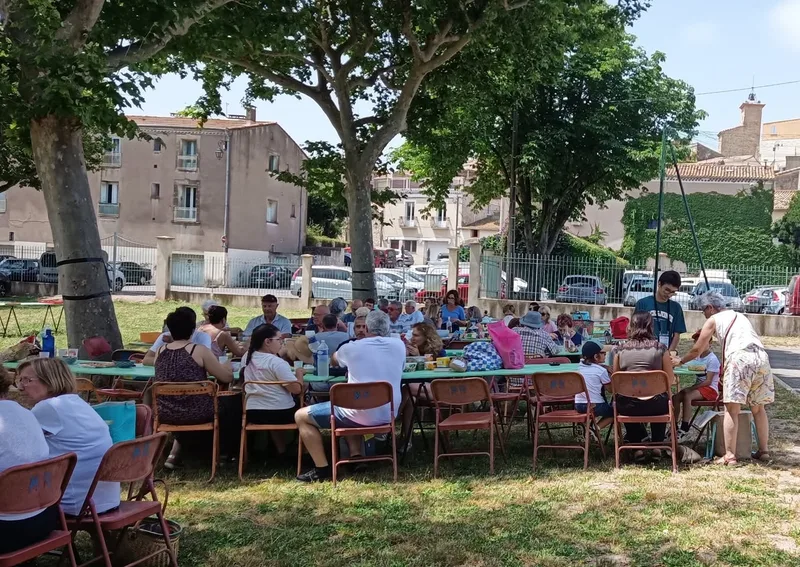 Habitants réunis à des tables sous les arbres à Roujan