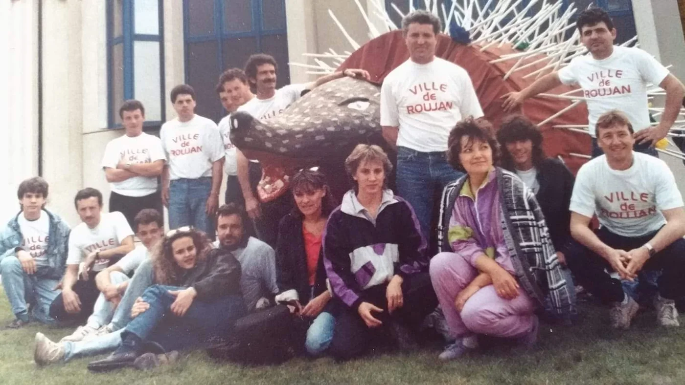 Un groupe pose autour du Roumégaïre ; plusieurs personnes portent un tee-shirt Ville de Roujan.